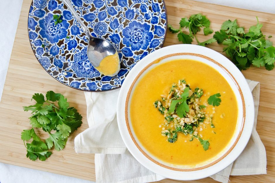 orange carrot ginger soup with peanut cilantro herb garnish on top